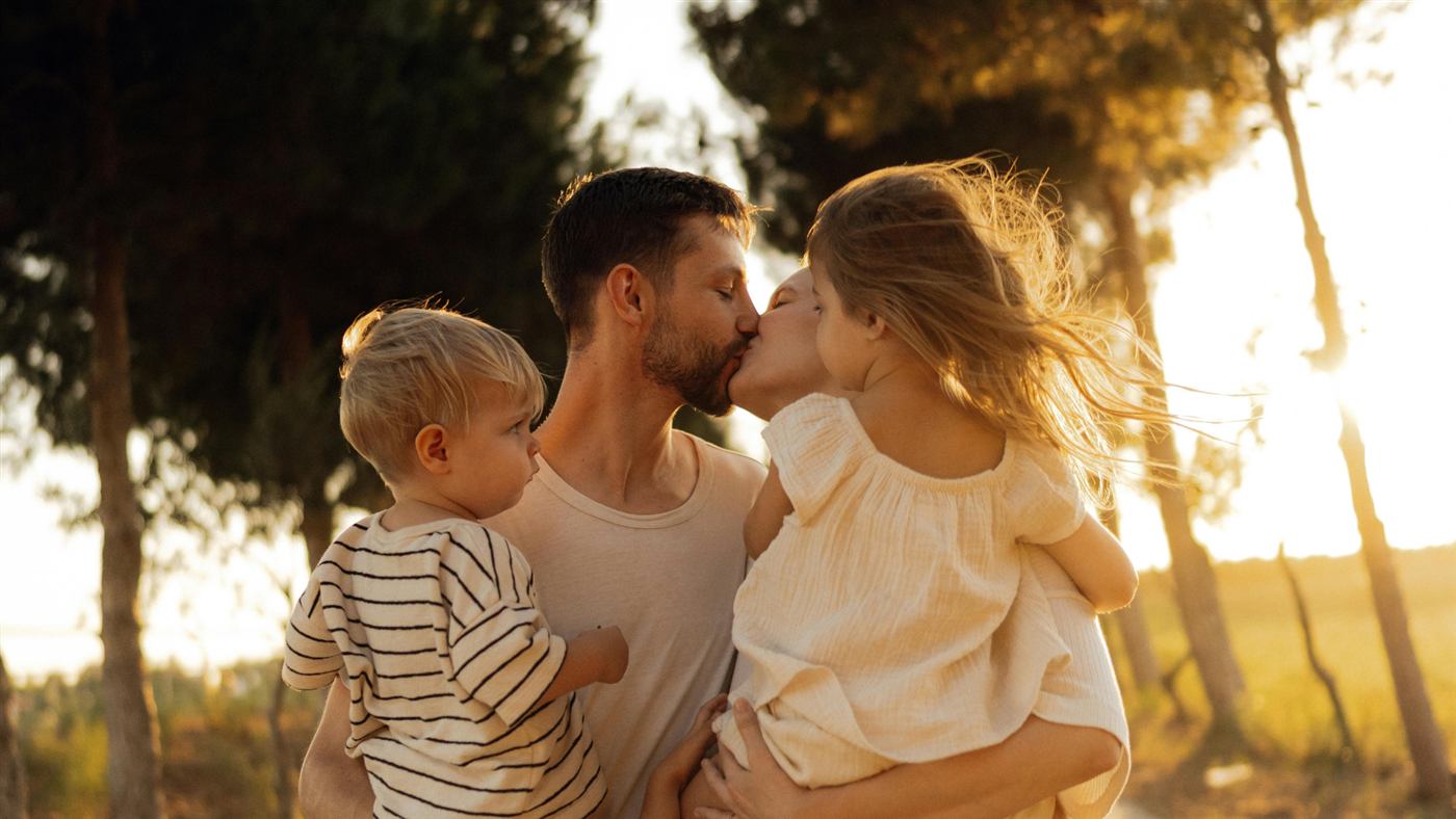 Família se abraçando e se beijando ao ar livre, luz de fim de tarde