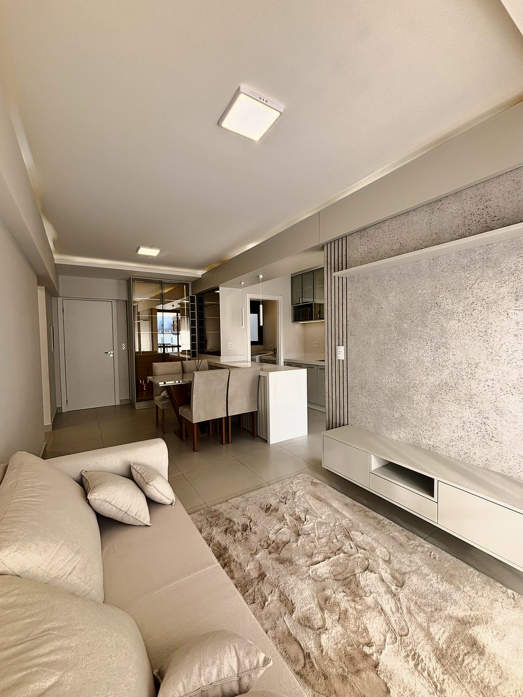 Residencial Sette — Sala de estar com painel de TV do apartamento decorado