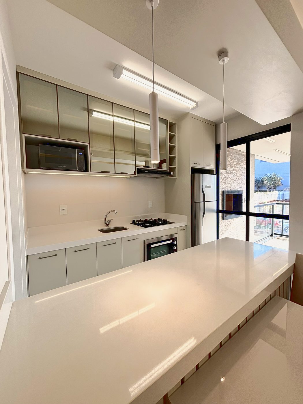 Residencial Sette — Cozinha com bancada em pedra e acesso à sacada